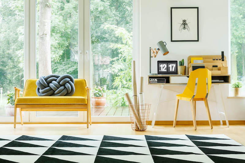 Sunny home office interior with a yellow chair and desk
